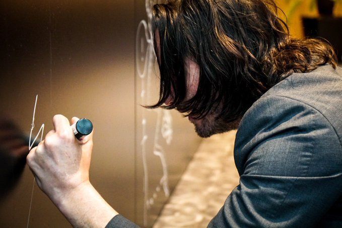 Киану Ривз оставляет подпись на стене для гостей | Источник: twitter.com/HIDEO_KOJIMA_EN