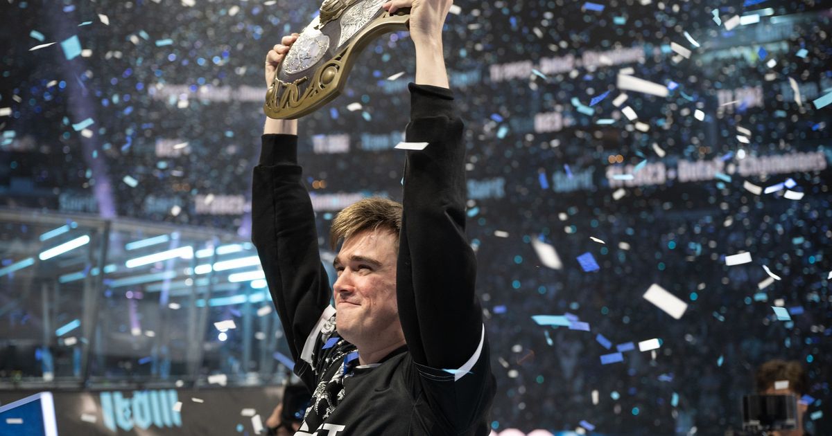 киберспортсмен радуется победе подняв руки на сцене